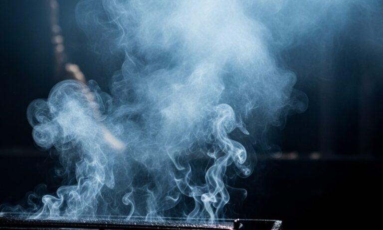 A person holds a cigarette in front of a cloud of smoke, creating a hazy atmosphere around them