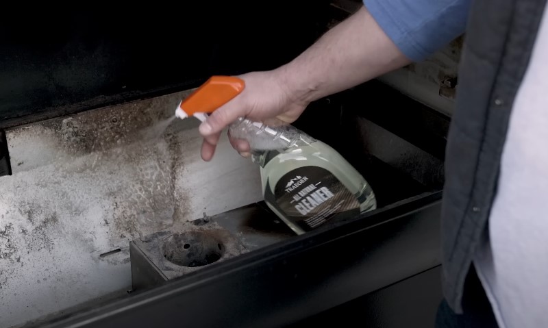 A person cleaning a stove with a spray bottle