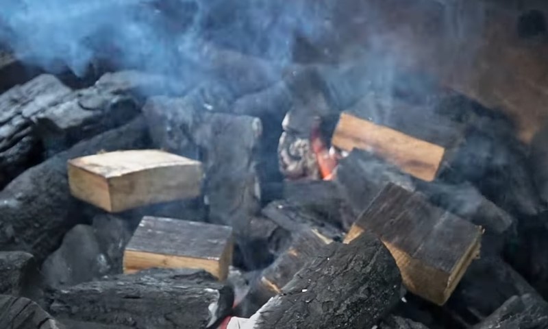 Close-up of glowing wood logs burning in a fire, with flames and embers creating a warm, flickering light