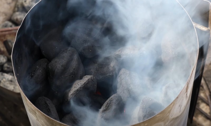 A close-up of a metal pan filled with black coal, showcasing its texture and sheen
