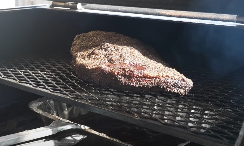 A large piece of meat sizzles on a grill