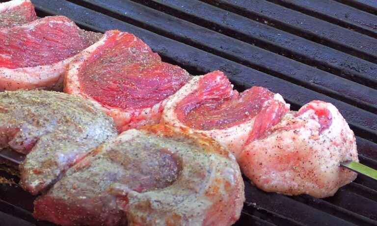 Steak sizzling on a grill, with visible grill marks and smoke rising